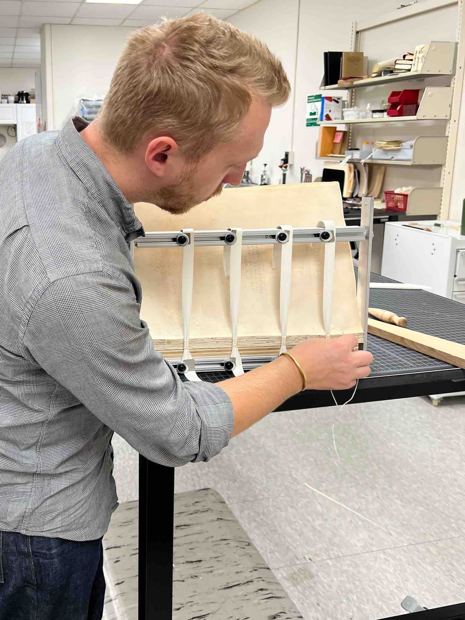 Garrett Sumner, conservation librarian with MSU Libraries, re-sewing “Geographia.”